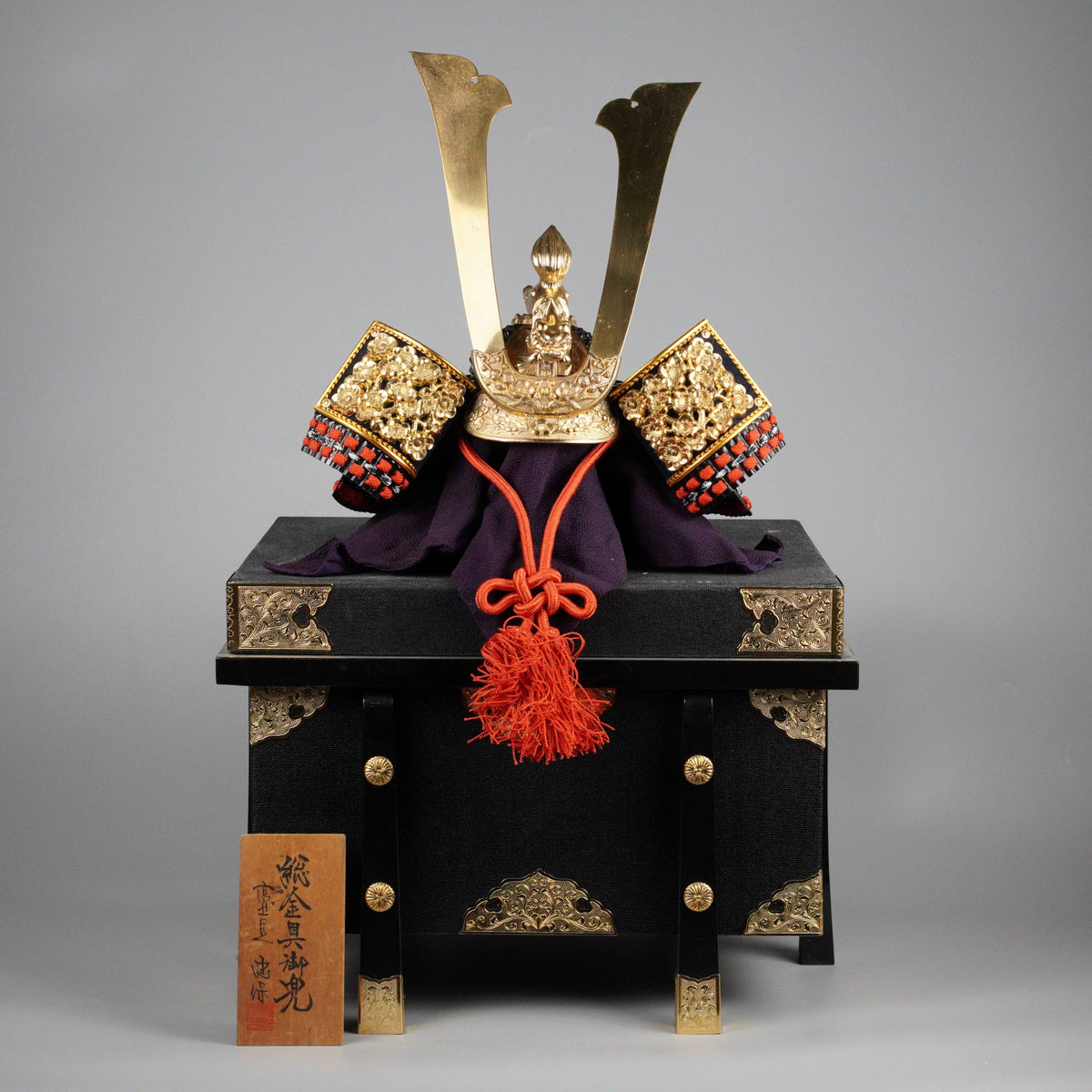 Samurai kabuto helmet on black lacquered display box, front view